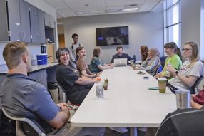 Students meeting for a research lab meeting at a long table in our Psychology research lab space