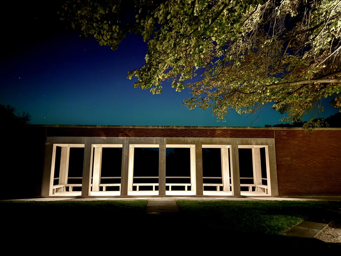 Photo shows a brick wall with a window looking out onto a dark field.