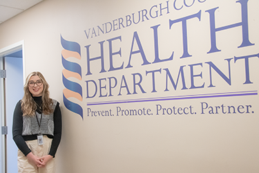 student standing in front of health dept. sign