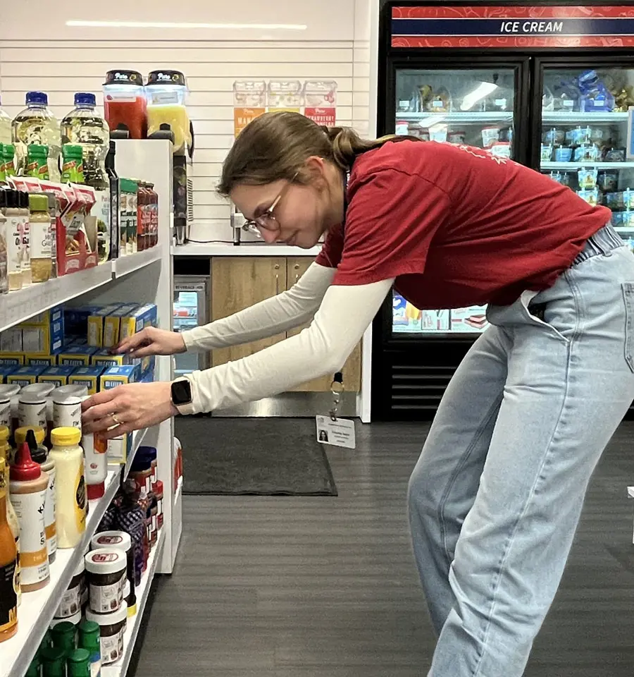Student picking up food from a store shelf